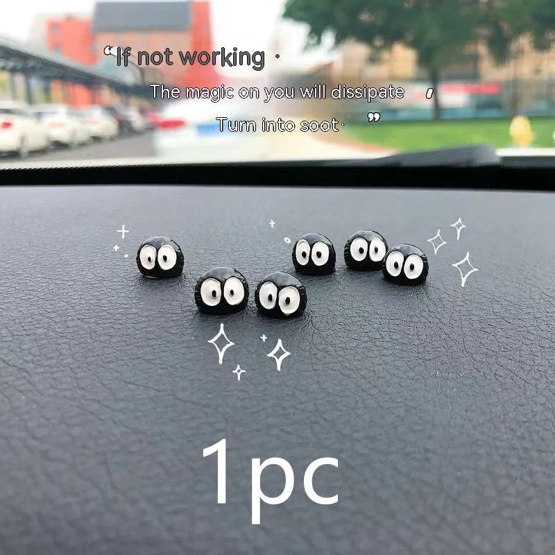 Small black resin coal ball cartoon decoration on a car dashboard.