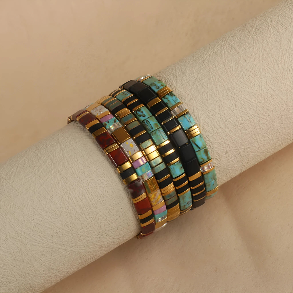 Geometric glass beaded bracelet in milky white, black, green, blue, or red on a white background.