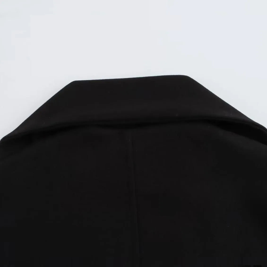 Women's long black polyester overcoat with artificial fur collar and pockets, showing extended length.