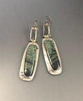 Close-up of simple geometric drop earrings with a two-colour marble pattern finish.