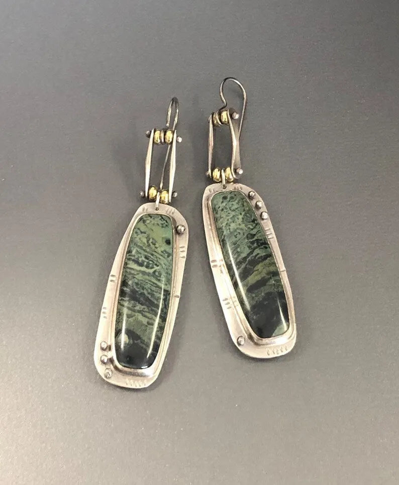 Close-up of simple geometric drop earrings with a two-colour marble pattern finish.