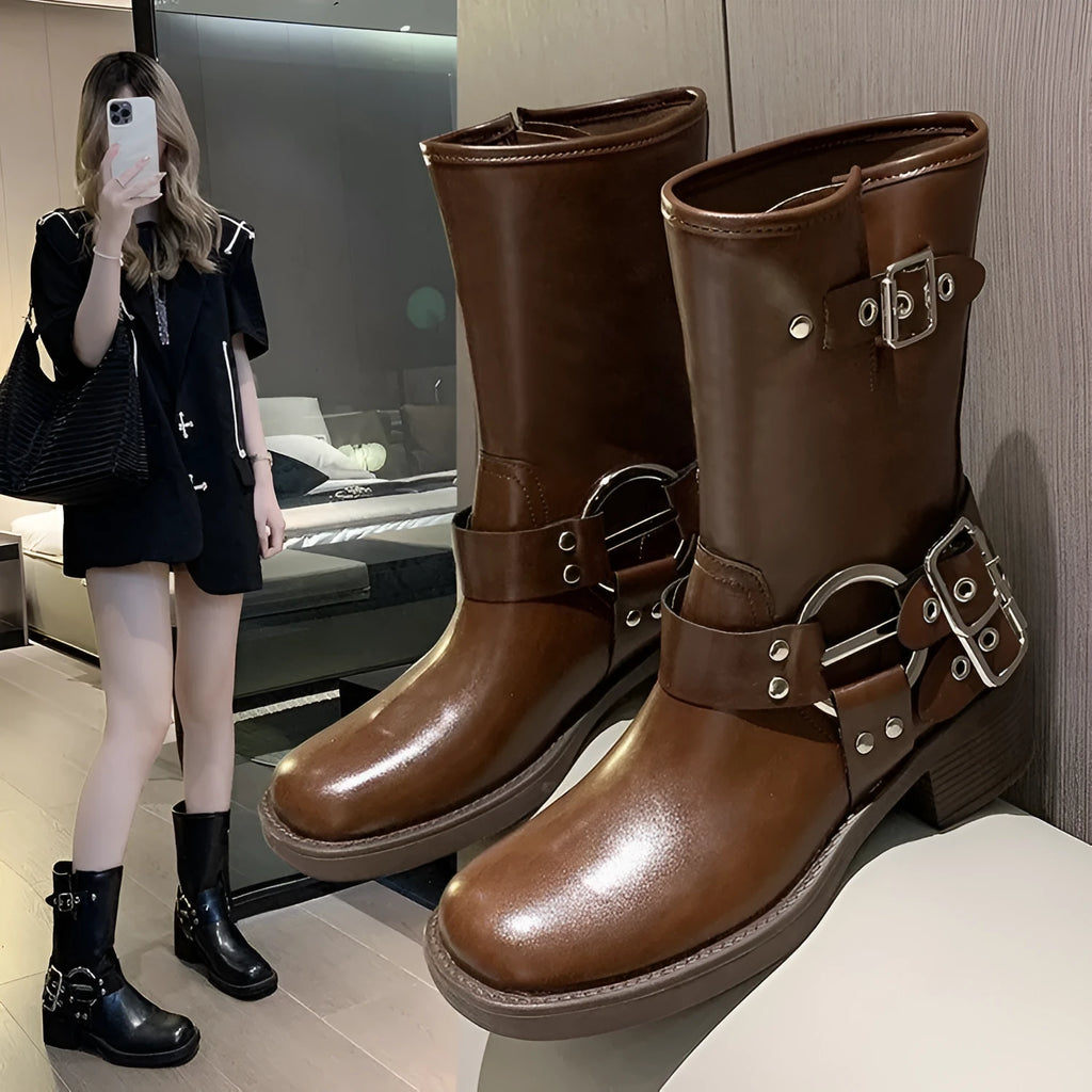 Women's black mid-calf platform boots featuring a large belt buckle on the shaft.