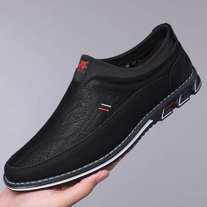 Men's black casual slip-on shoe with leather toe cap and decorative stitching on fabric upper.