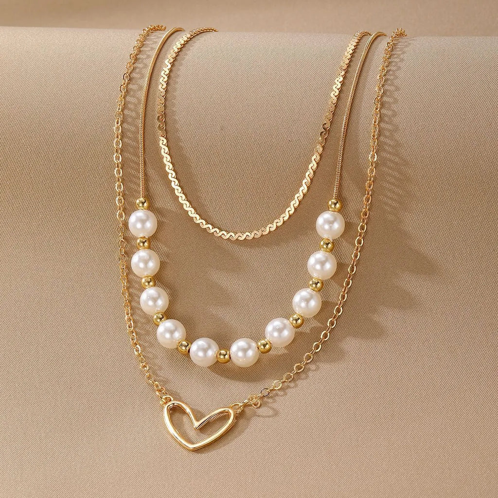 Vintage gold necklace with love heart pendant on a pearl chain, adjustable length.