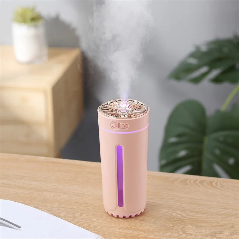 Black wireless ultrasonic humidifier with colourful lights, shown next to a USB cable on a desk.