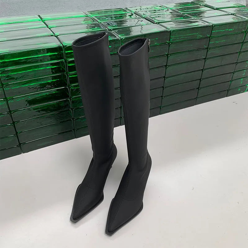 Black pointed toe below knee stiletto heel boots with a back zip, shown on a foot.