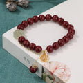 Women's cinnabar bracelet with purple gold sand finish and traditional fu character charm with tassel detailing