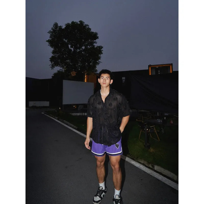 Man wearing a loose-fit black short-sleeved shirt with a large white three-dimensional floral print.