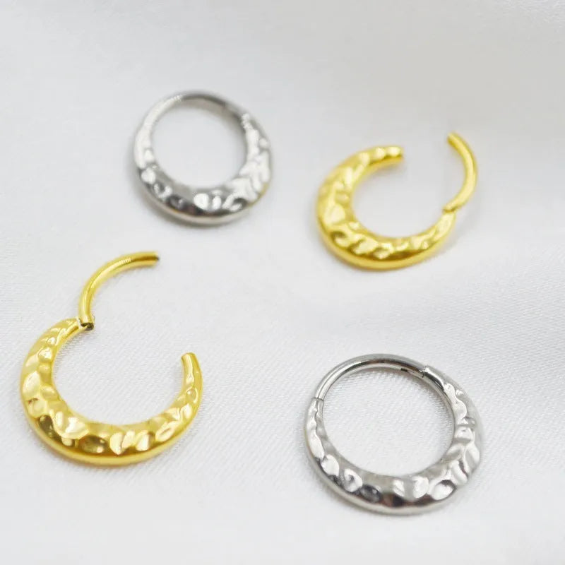 Close-up of a concave-convex carved titanium nose ring in gold and silver finishes.