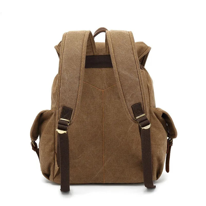 Retro canvas backpack in army green colour with antique bronze hardware, shown with a laptop to scale.