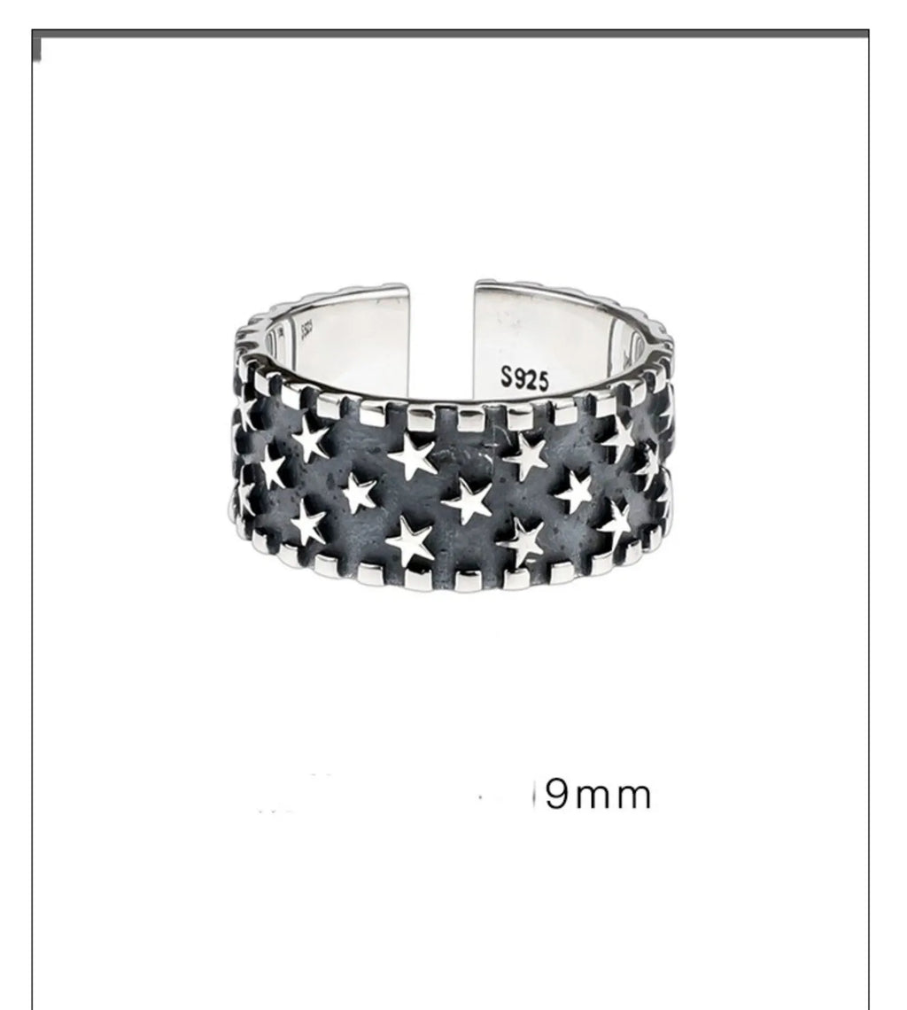 Close-up of an adjustable silver ring with a geometric multi five-pointed star design on a neutral background.