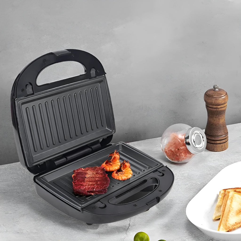 Black electric sandwich pan with double-sided heating, brushed stainless steel lid, and non-stick cooking plates.