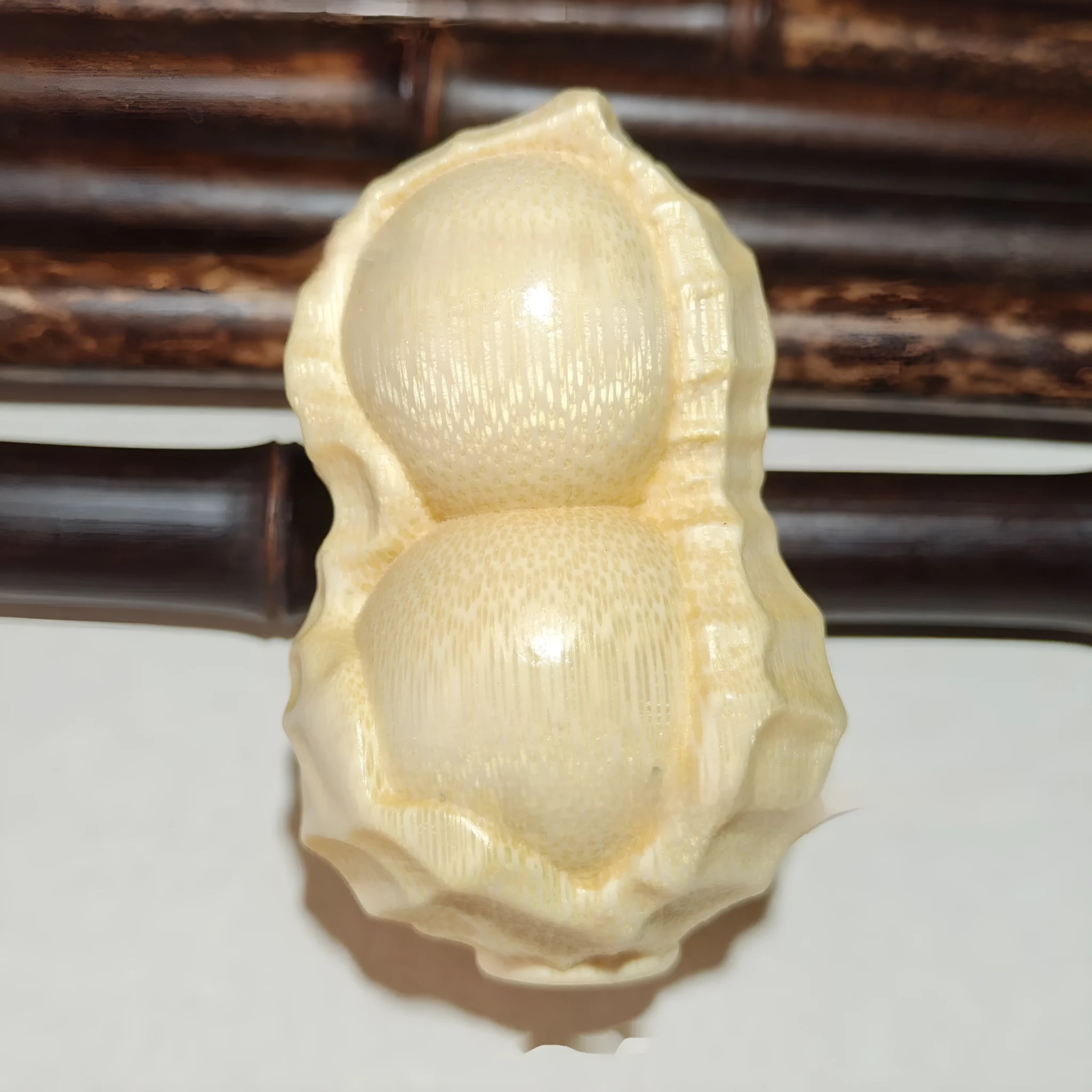 Solid bamboo peanut-shaped ornament with natural wood grain on wooden surface