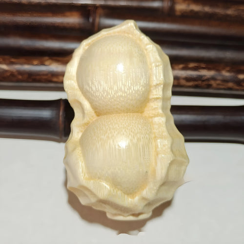 Solid bamboo peanut-shaped ornament with natural wood grain on wooden surface