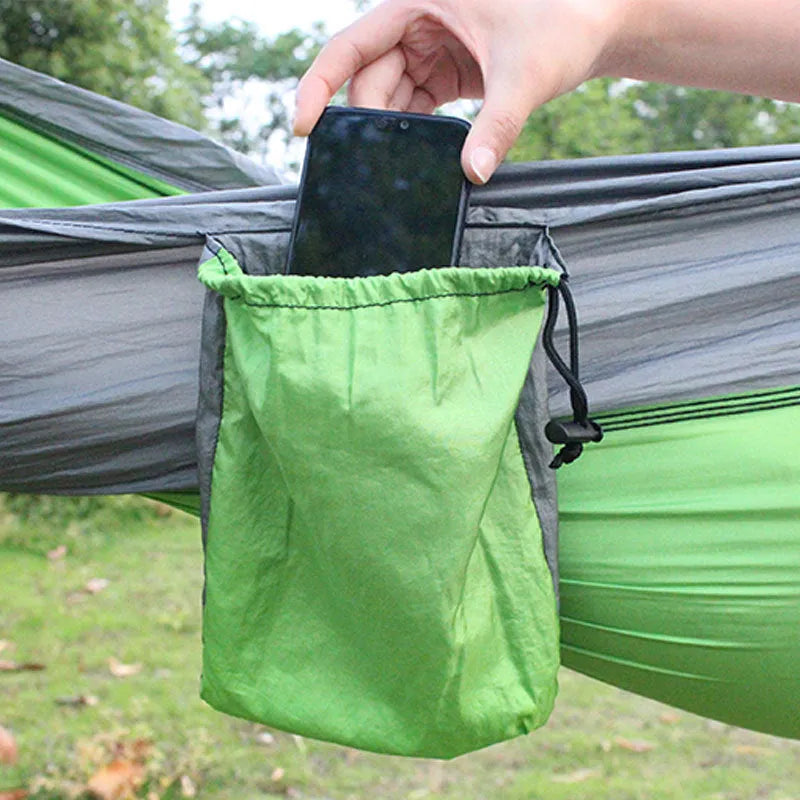 Blue outdoor camping hammock made from parachute nylon fabric, hanging between two trees.