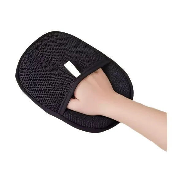 Black pet hair removal glove with silicone bristles on a hand, grooming a dog.