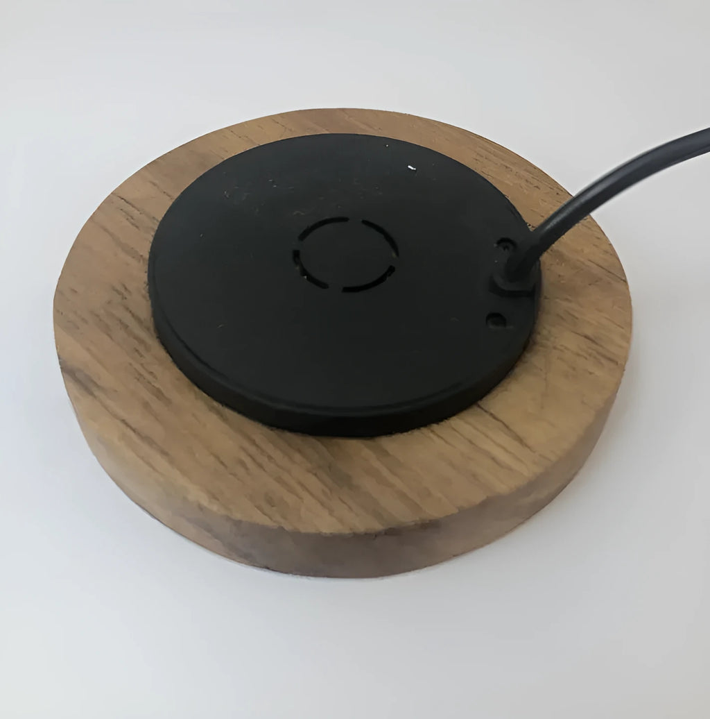 Black 75mm round wireless charging disc for embedding into desks, compatible with iPhone and Samsung phones.