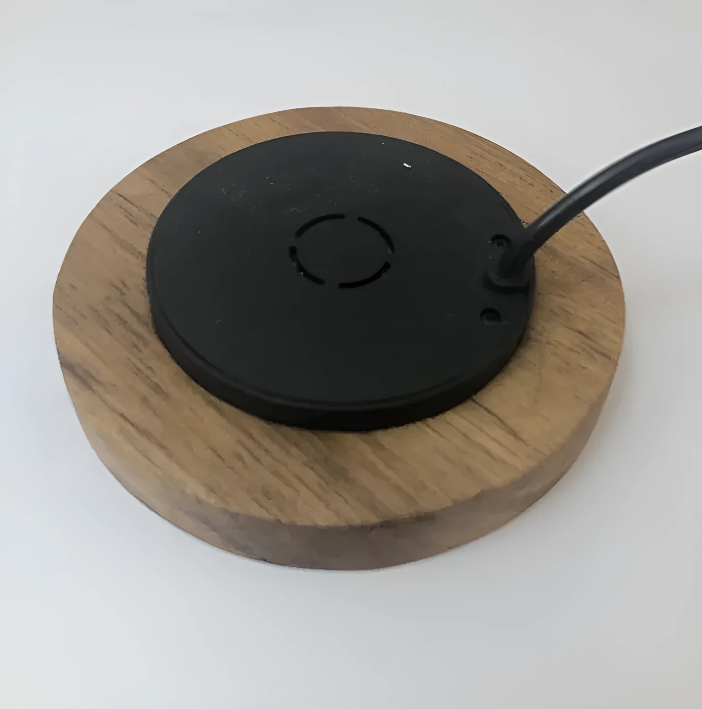Black 75mm round wireless charging disc for embedding into desks, compatible with iPhone and Samsung phones.