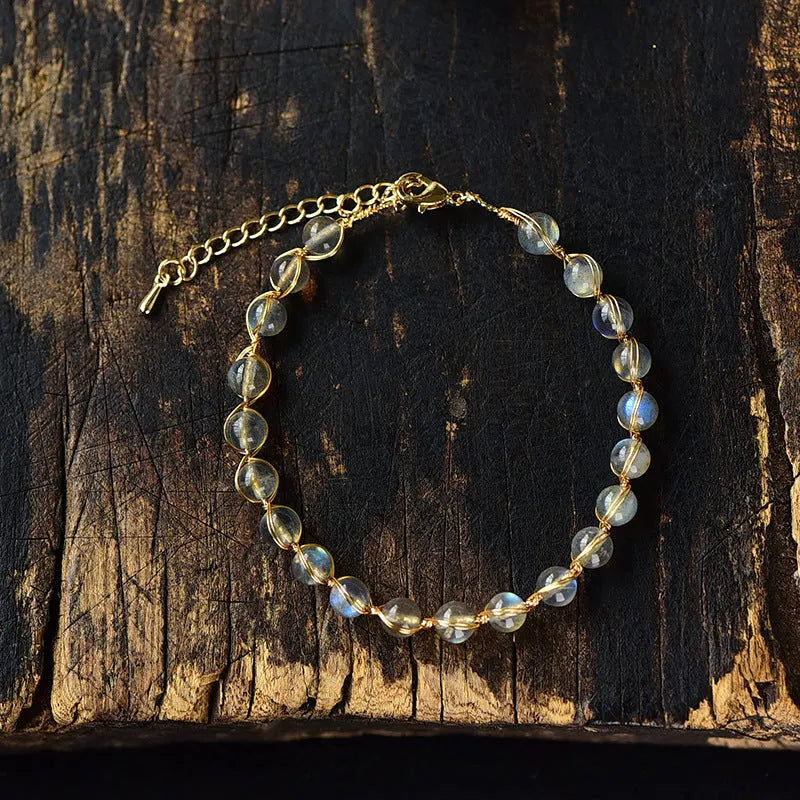 Blue moonstone and gold tone bracelet with 6mm beads on a wrist.