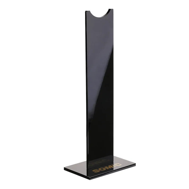Pink and black detachable headphone stand with silicone base on a desk.