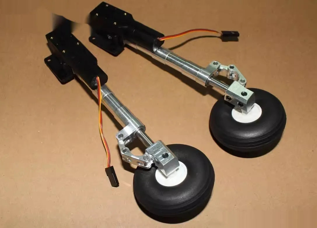 Pair of silver alloy retractable landing gear with shock absorbers and black rubber wheels for RC model aircraft.