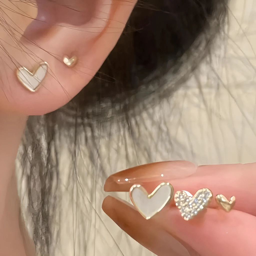 Three pairs of heart shape alloy earrings in gold, black, black white, and pink colours with love design elements