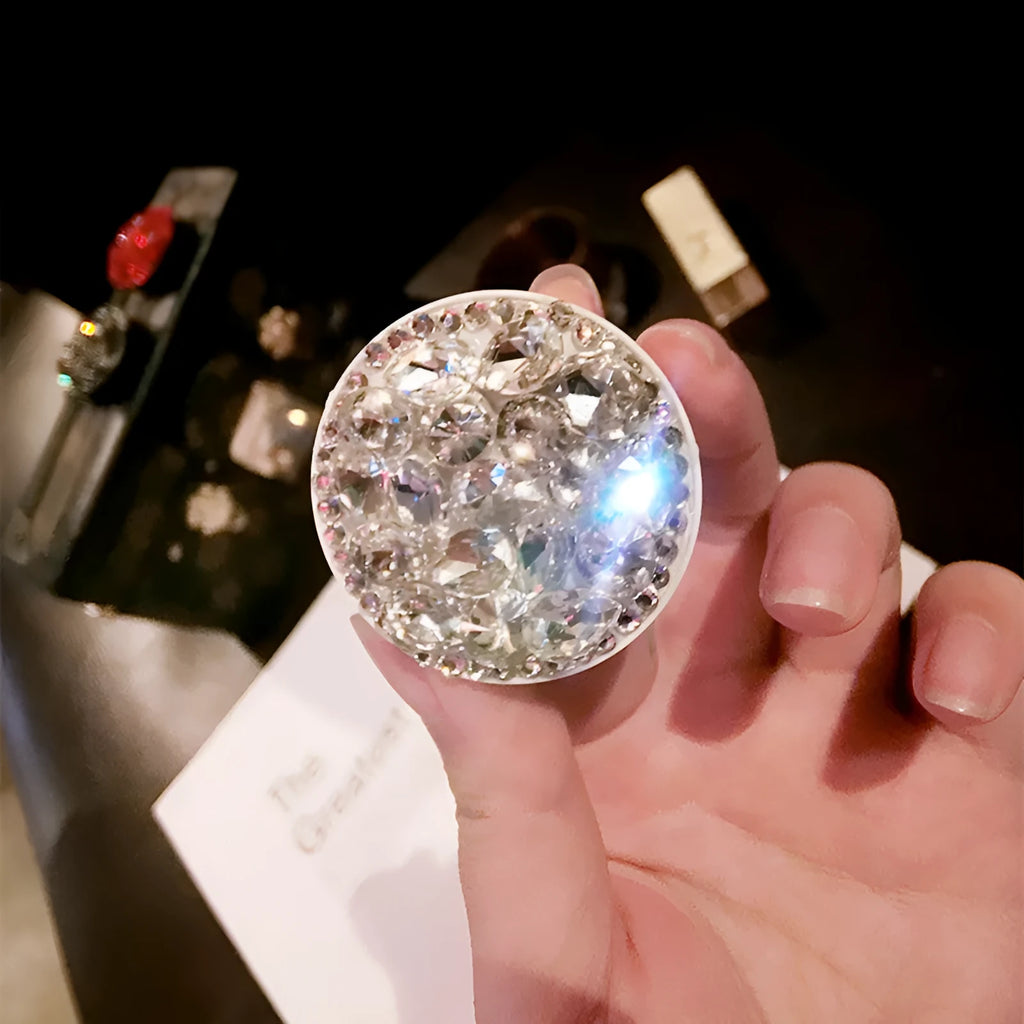 Rhinestone airbag mobile phone holder with telescopic bracket, shown in one of seven colour options for hands-free viewing.