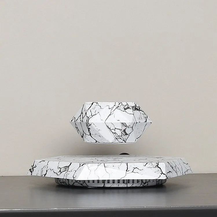 Marble-coloured magnetic levitating plant pot floating above surface with small plant