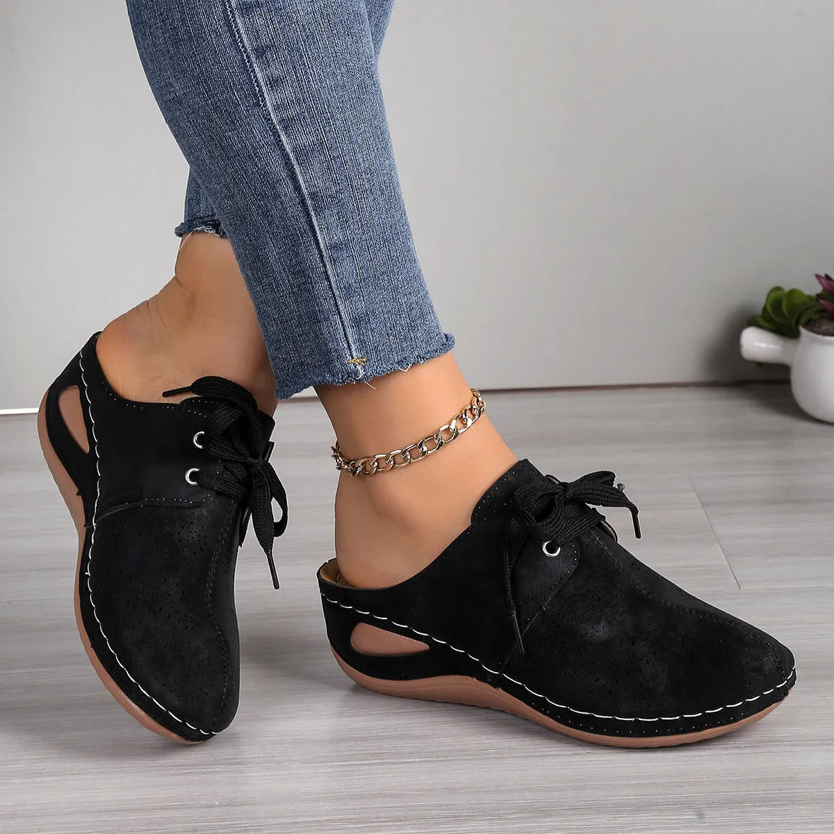 Women's black lace-up baotou slippers with a suede upper and rubber sole on a neutral background.
