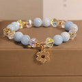 Women's adjustable bracelet with aquamarine crystal four-leaf clover charm and pearl detail.
