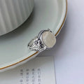 Antiqued copper ring with white stone and adjustable U-shaped opening.