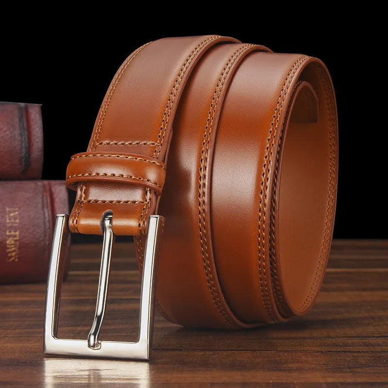 Men's black leather belt with a silver alloy pin buckle on a wooden background.