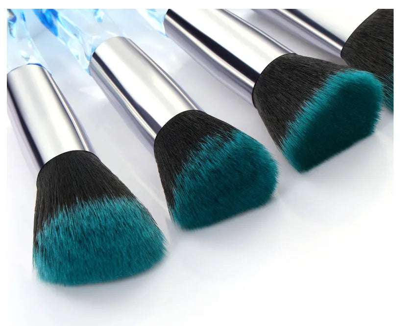 Ten clear crystal-handled foundation brushes with artificial fibre bristles, laid out in a set.