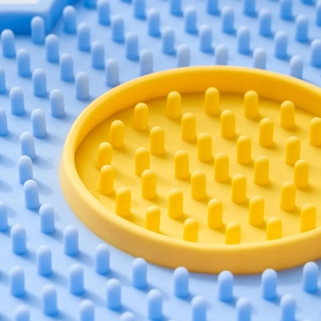 Flower-shaped blue silicone pet lick mat with suction cups on a tiled floor.