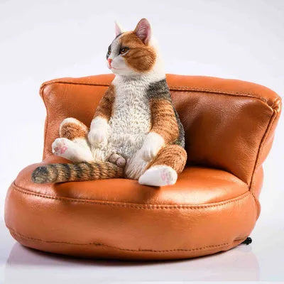 Small lazy cat resin model ornament with fabric art sofa on a car dashboard.