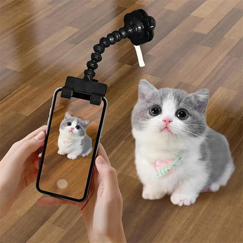 Black plastic pet photography tool with treat clip and phone holder, shown rotated to adjust angle.