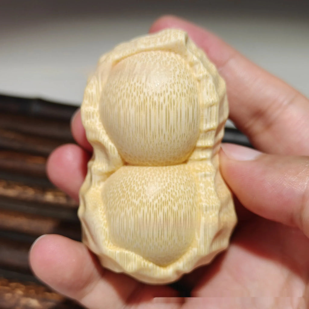 Solid bamboo peanut-shaped ornament with natural wood grain on wooden surface