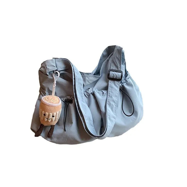 Green pleated folding crossbody student bag with a front split pocket and long strap.