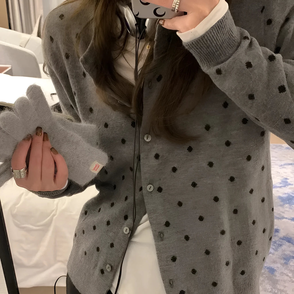 Women's grey dot patterned knitted cardigan with crochet flower detail on sleeve.