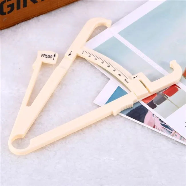Clear acrylic skin fold fat caliper for body fat measurement showing measurement scale.
