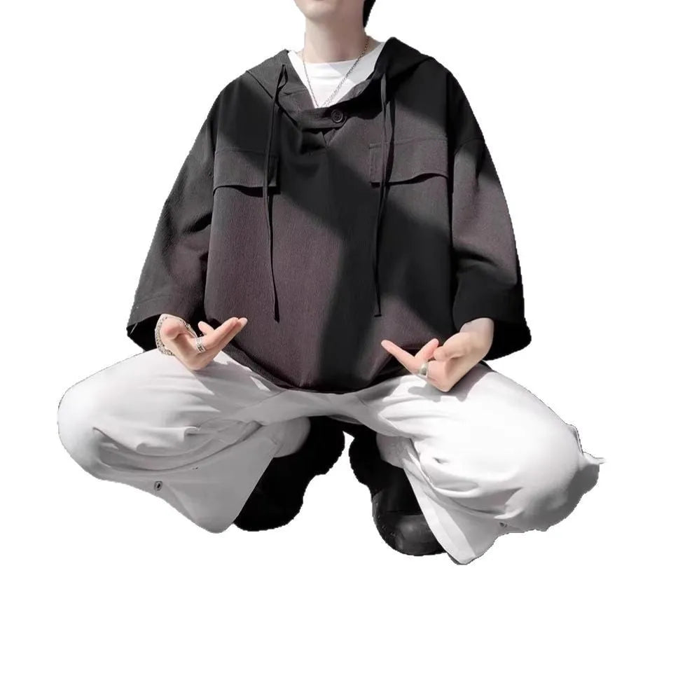 Man wearing a loose black hooded short sleeve t-shirt, a summer casual pullover top.