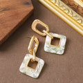 Pair of hollow square earrings with bevelled corners in a metallic finish, shown on a white background.