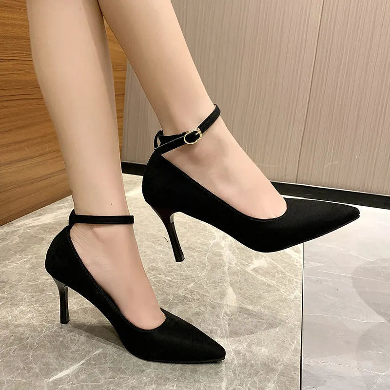 Women's black stiletto heel pump shoe with buckle detail on a white background.