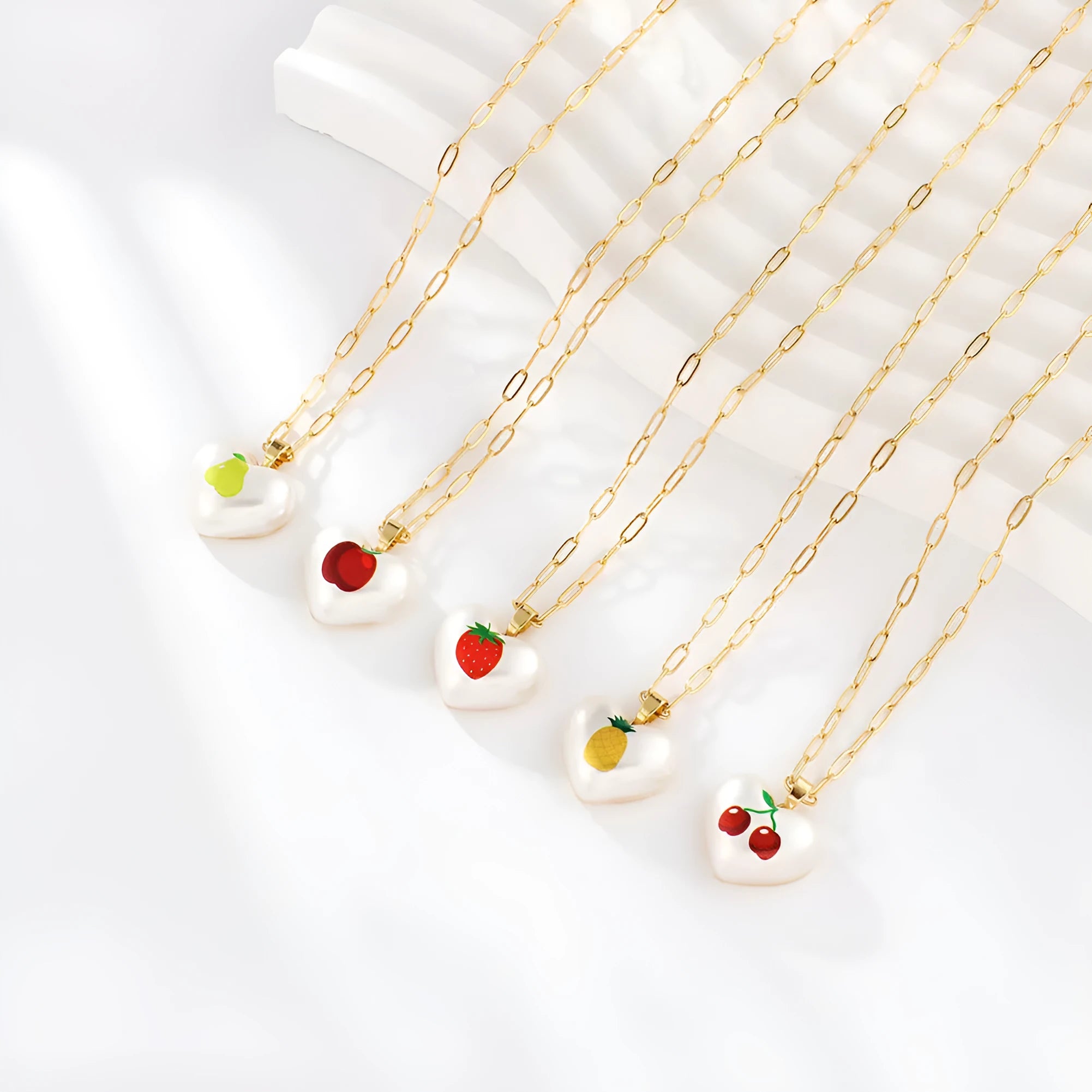 Geometric fruit pendant necklace on an adjustable chain, showing apple, cherry, pear, pineapple, and strawberry charm options.
