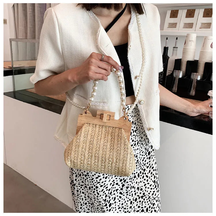 Women's straw woven shoulder bag with pearl chain trim showing internal compartments