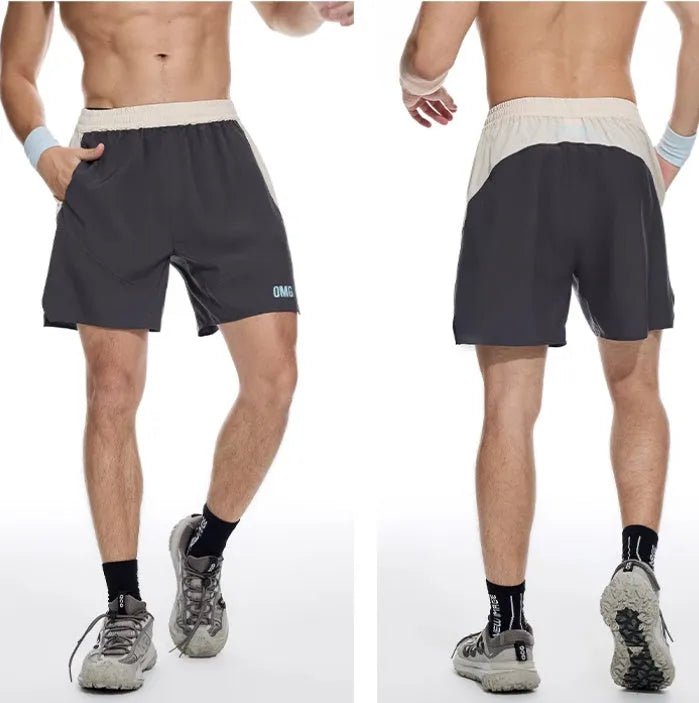 Men's loose grey workout shorts with elastic waist and lace-up fly on a gym floor.