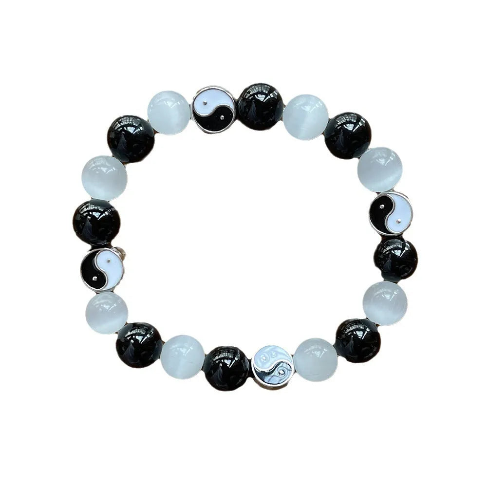 Opal and black agate Tai Chi bracelet with 10mm polished stone beads on a wrist.