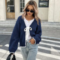 Gray lace-up front cardigan with crocheted flower detail on a model, showing loose long sleeves.