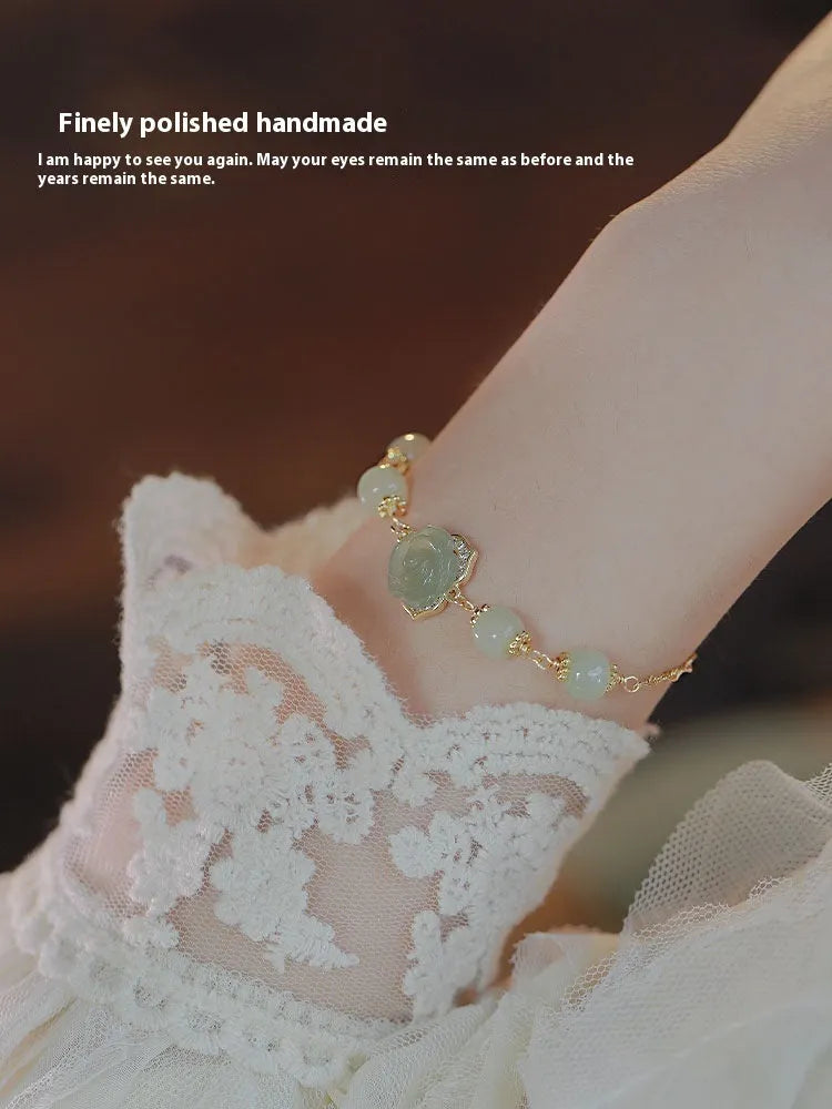 Original design women's bracelet with a Hetian Jade rose and 14K gilded details on a wrist.
