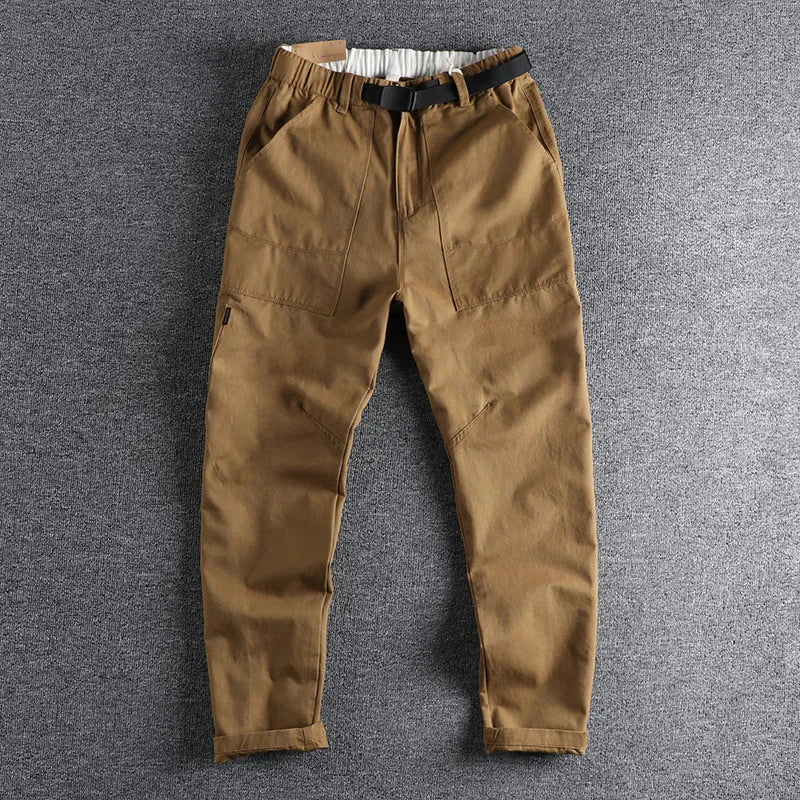 Men's khaki cotton work trousers with an N I buckle belt on a mid-rise waist.